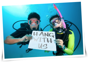 singles snorkeling underwater with sign that says hang with us