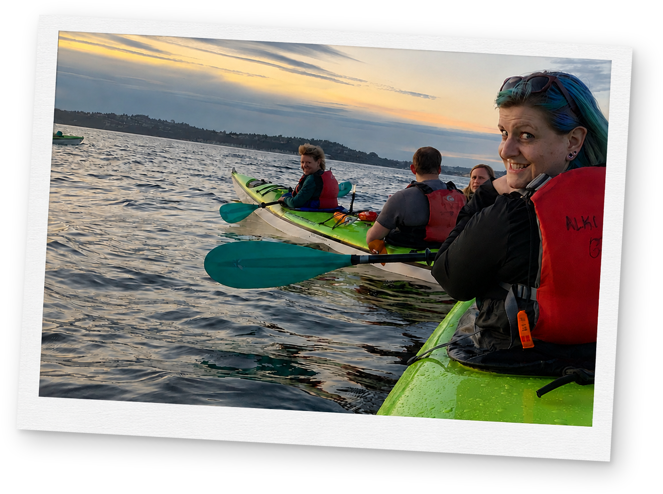 Two people kayaking together on calm water at sunset.